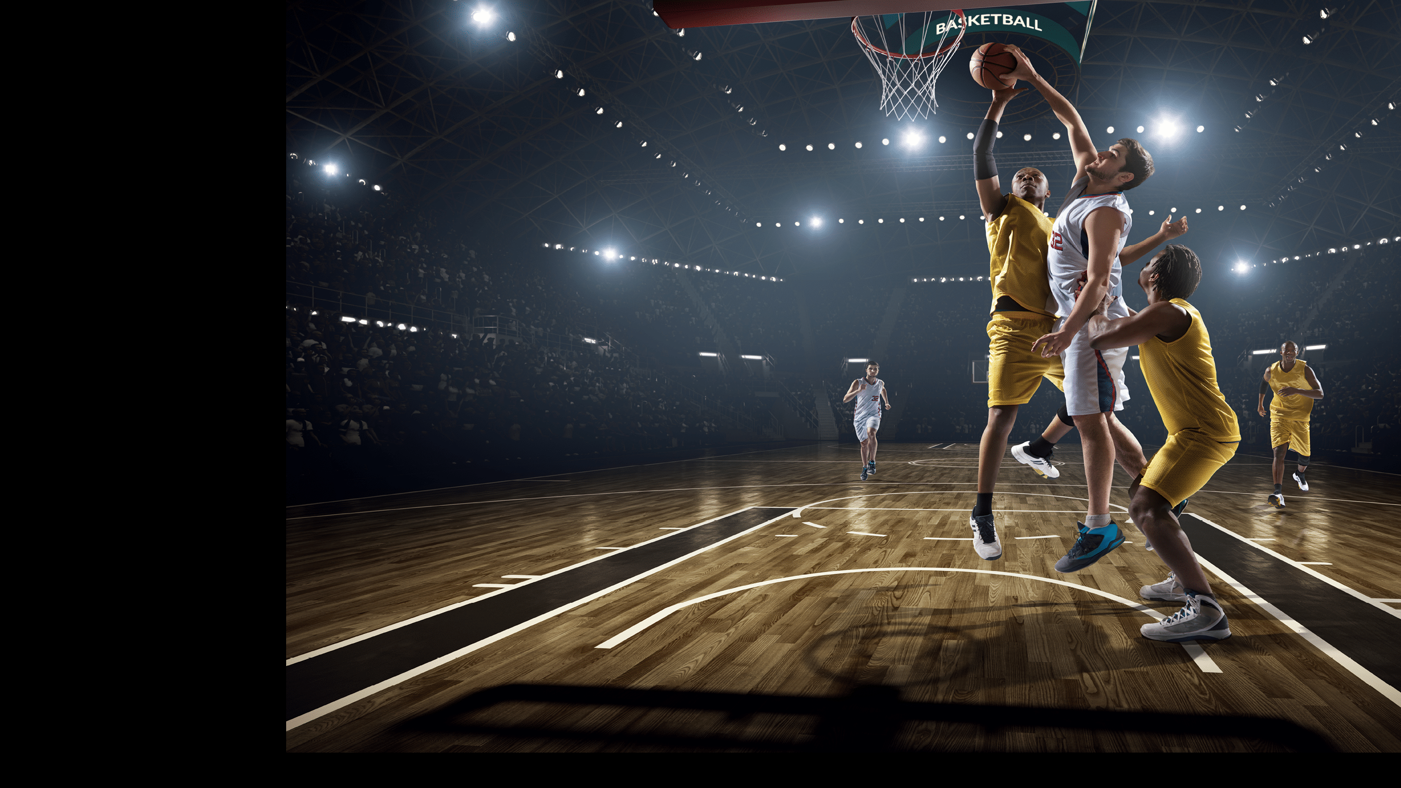 Low angle view of a professional basketball game  A player is in mid air holding ball about to score a slam dunk, but the player from the opposite team is ready to block him   A  game is in a indoor floodlit basketball arena  All players are wearing generic unbranded basketball uniform 
