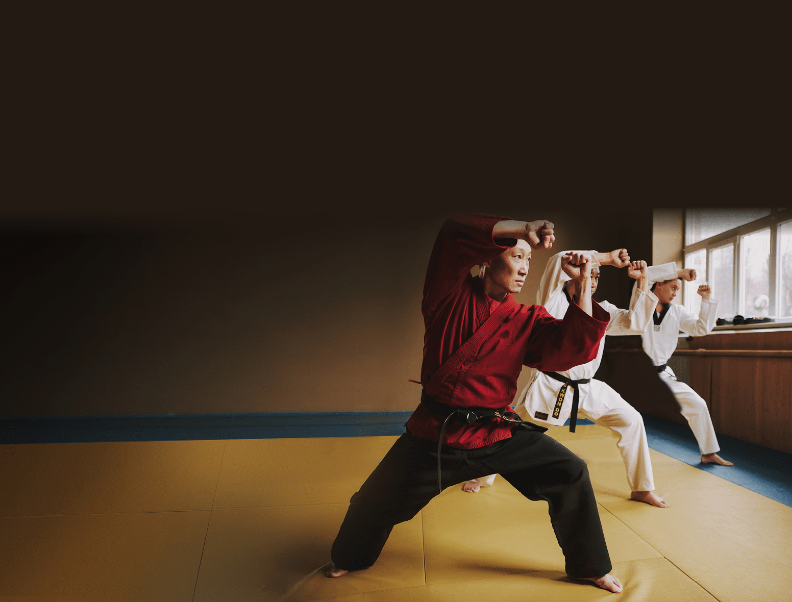 Sensei and two martial arts students with black belts training together 