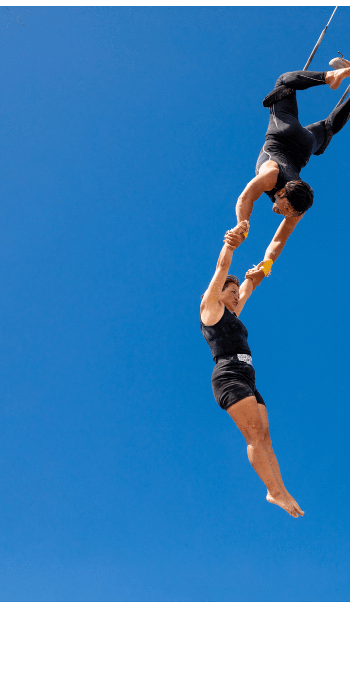 Trapeze artists swinging together in the sky