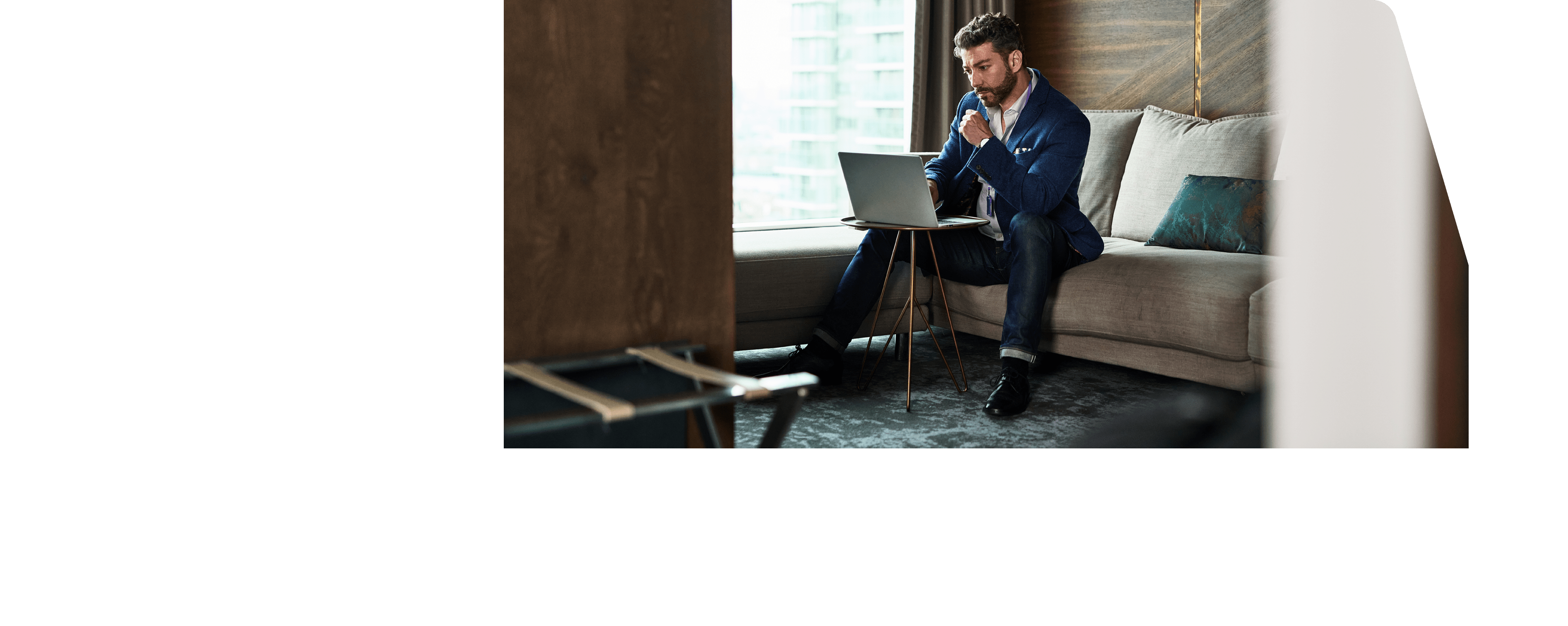 Man working away from home on business trip sitting on sofa and concentrating, looking at screen, contemplation, serious, planning