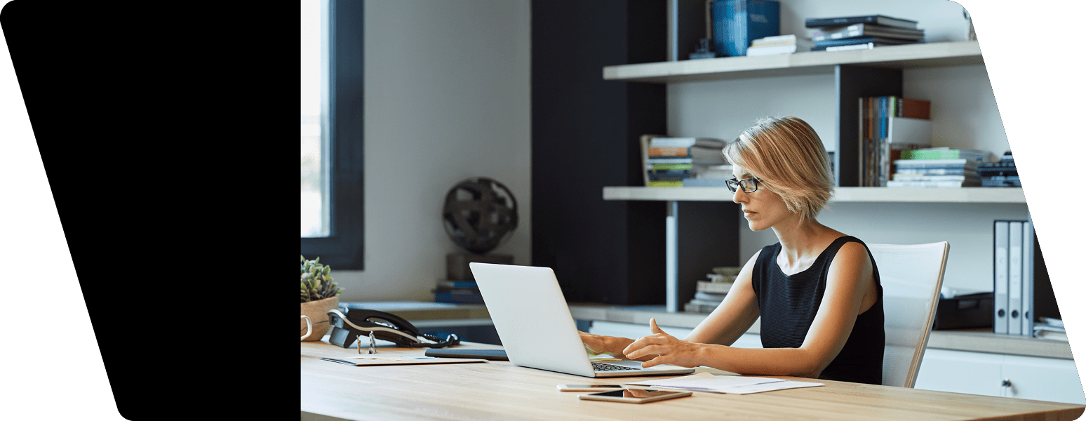 Businesswoman using laptop at desk  Confident female professional is working in textile factory  Executive is with short brown hair 